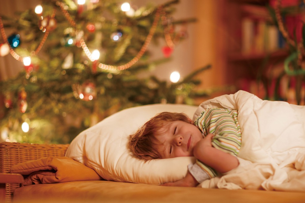 Little cute blond boy sleeping under Christmas tree